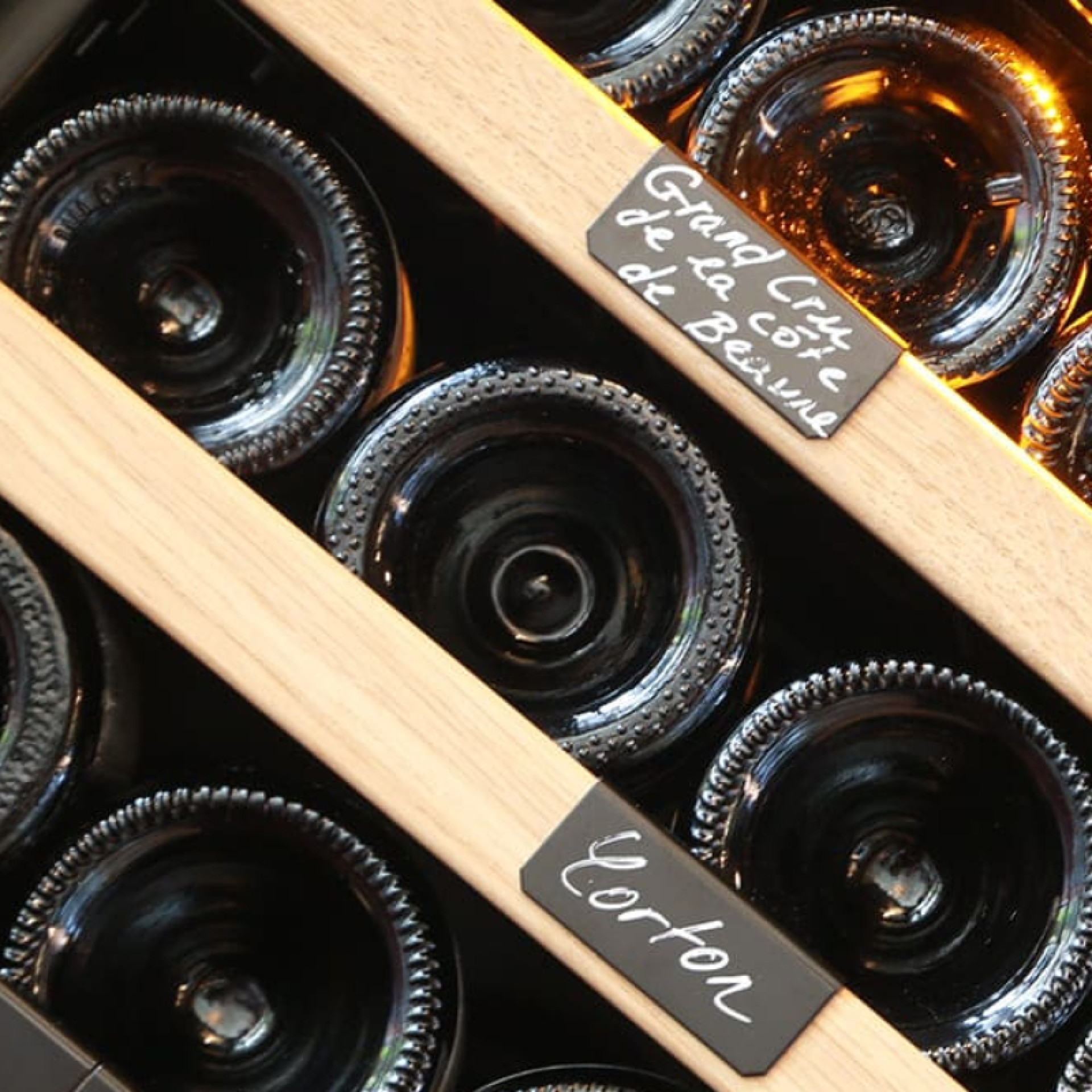 Lagerung im Weinkeller – Metallregale mit einzelnen Flaschenhaltern, Front aus naturfarbenem Eichenholz. Lagerung im Weinkeller – Metallregale mit einzelnen Flaschenhaltern, Front aus naturfarbenem Eichenholz.