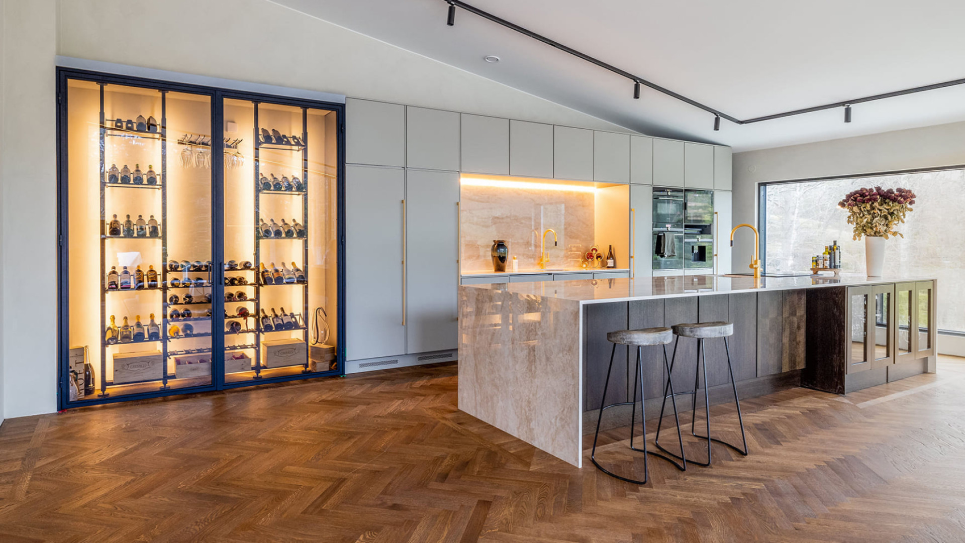Traumweinkeller – Beispiel für die Gestaltung einer in die Wand eingebauten Weinvitrine eines modernen und luxuriösen Innenraums mit einer Kücheninsel aus Marmor.