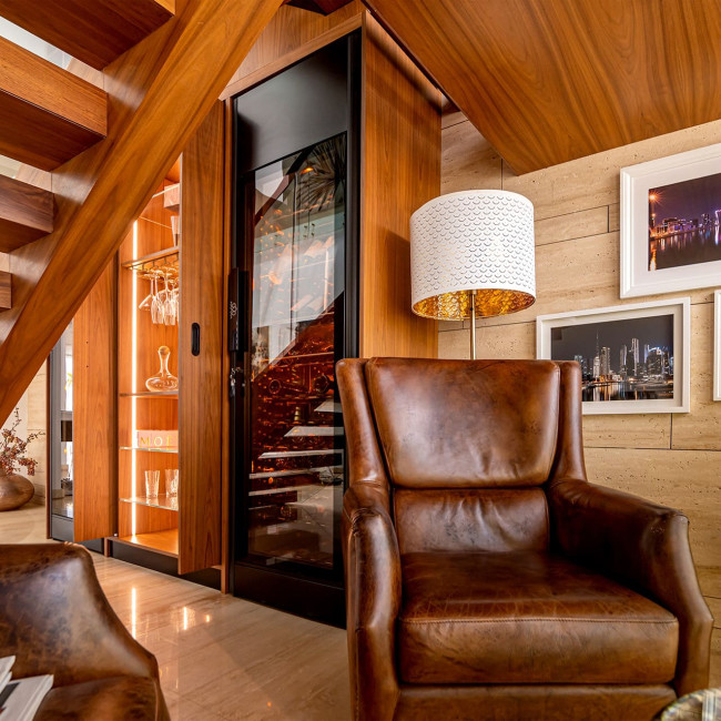 ShowCave Weinkühlvitrine, in ein maßgefertigtes Möbelstück unter einer Treppe integriert – gemütlicher Verkostungsraum mit Holz- und Lederdesign