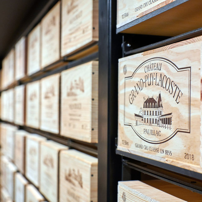Regal aus mehreren miteinander verbundenen Modulorack Elementen, das eine Weinwand mit Holzkisten auf einer schwarzen Metallstruktur bildet, mit einem industriellen und authentischen Design.